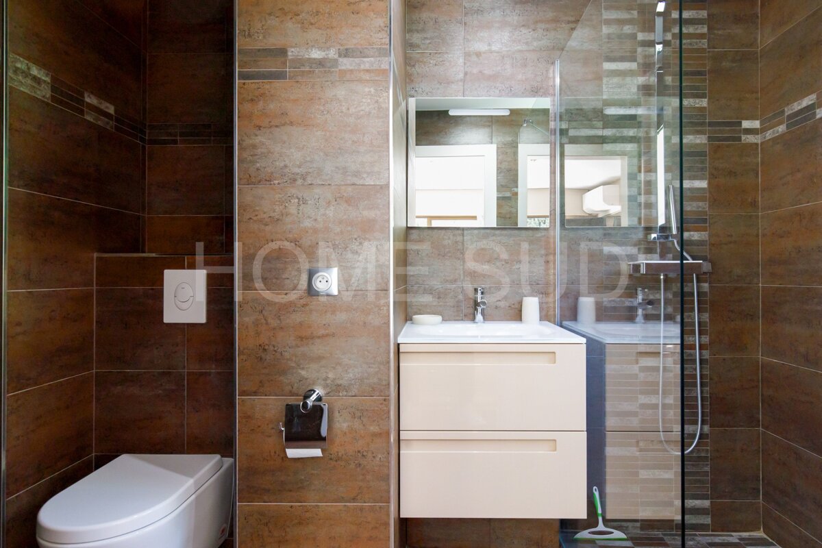 A bathroom with brown tiles and a sign that says home studio