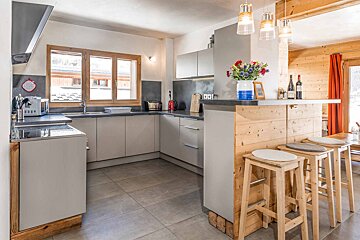A kitchen with stools and a vase of flowers on the counter