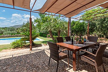 A table and chairs under a canopy with a bottle of wine on it