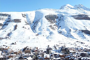 A snowy mountain with a ski resort in the foreground