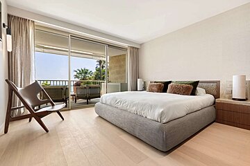 A bedroom with a large bed and a chair