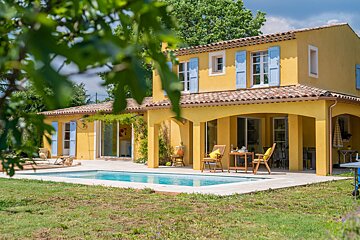 A yellow house with blue shutters and a swimming pool