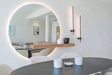 A dining room with a round mirror and candles on the table