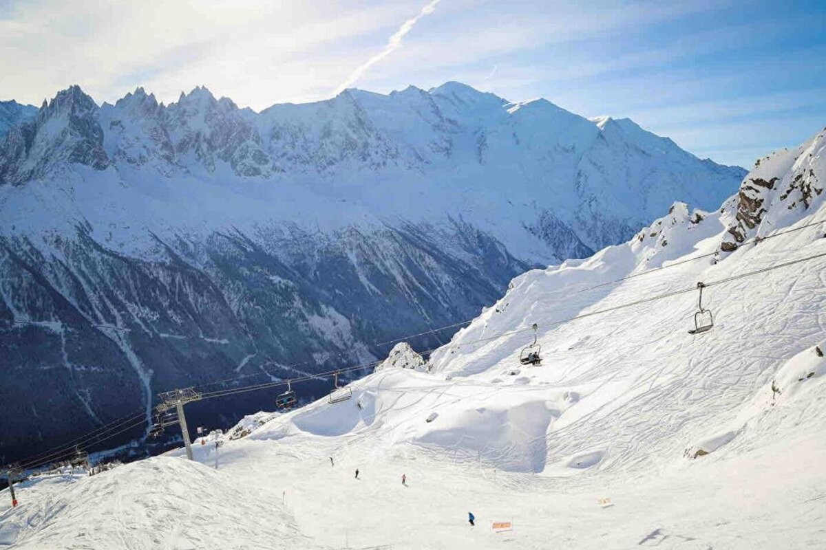 Skiers on a snowy slope with mountains in the background