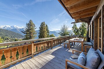 A balcony with a table and chairs overlooking the mountains