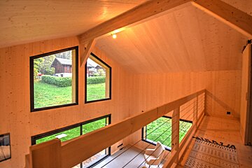 A wooden house with a view of a lush green field
