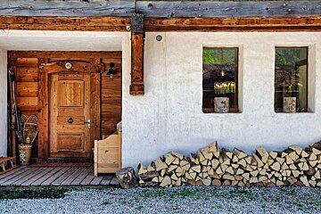 A house with a wooden door and a pile of logs in front of it