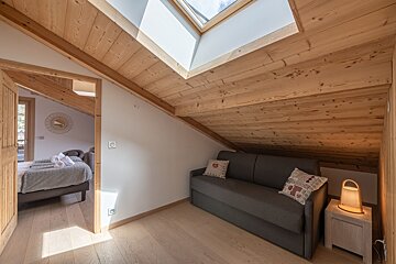 A bedroom with a couch a desk and a flat screen tv