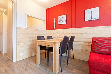 A wooden table and chairs in front of a red wall