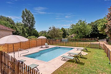 A large swimming pool surrounded by chairs and umbrellas