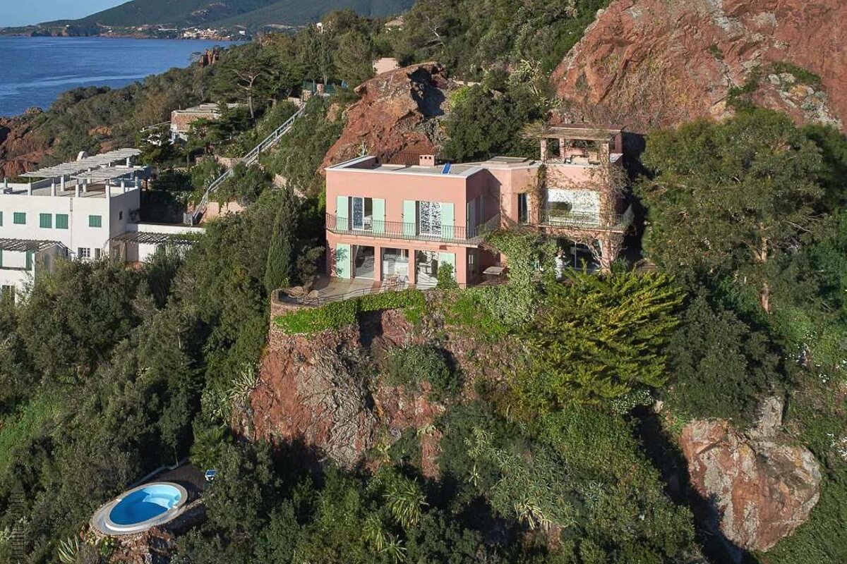 An aerial view of a house on a cliff overlooking the ocean