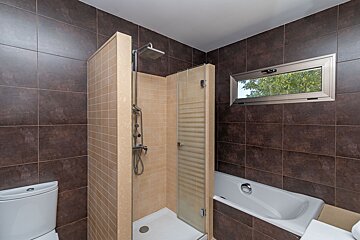A bathroom with a tub and a shower with a glass door