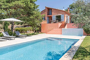 A large swimming pool in front of a house that says janssen by immobilier
