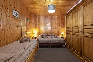 A bedroom with wood paneling and a bed