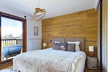 A bedroom with wood paneling and a bed that says white management