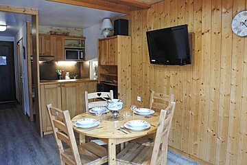 A lg television is mounted on the wall above the dining table