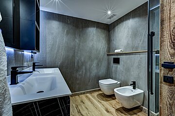 A bathroom with two toilets and a bidet