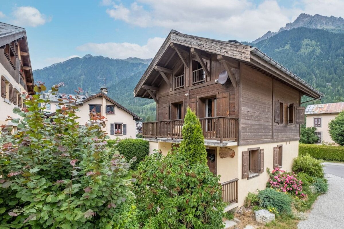 A small wooden house with a balcony and mountains in the background