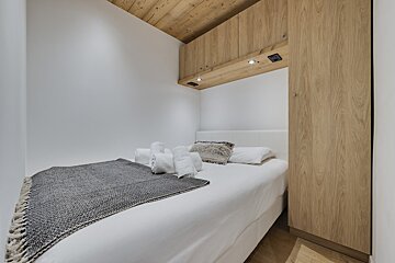 A bedroom with a white bed and wooden cabinets