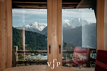 A view of the mountains through a window with the letters vjp on the table