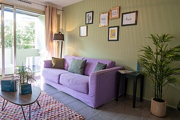 A living room with a purple couch and pictures on the wall that say love