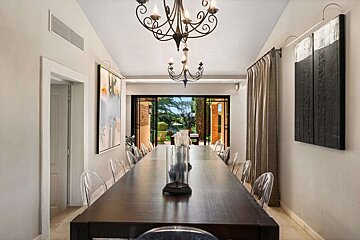 A dining room with a long table and chairs and a chandelier