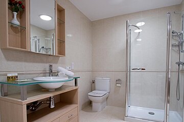 A bathroom with a toilet a sink and a glass shower