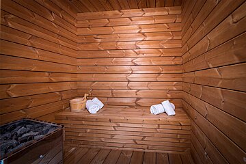 A wooden sauna with a bucket and towels on the bench