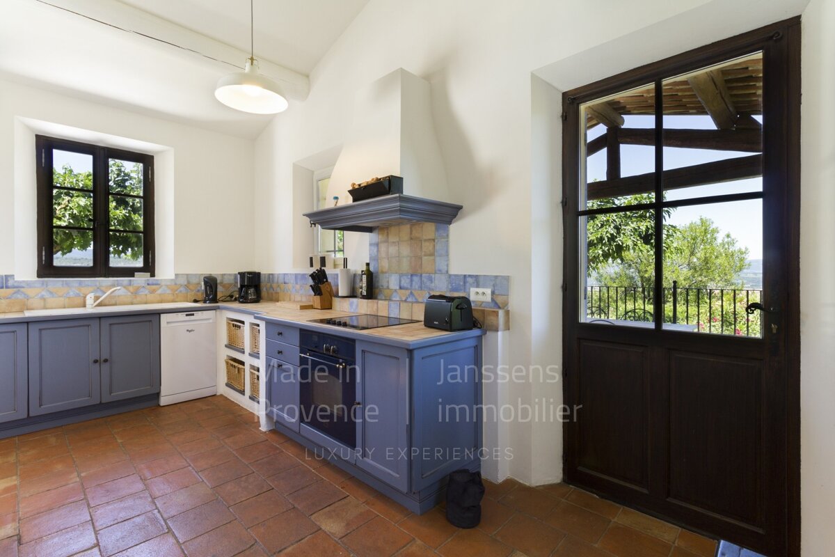 A kitchen with blue cabinets and a door that says janssens immobilier