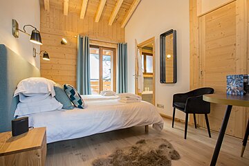 A bedroom with a single bed and a desk