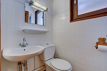 A bathroom with white tiles and a toilet and sink