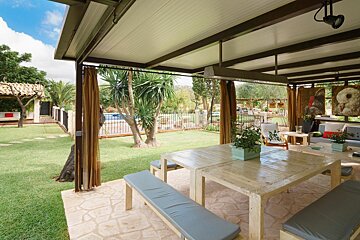 A patio with a table and benches under a canopy