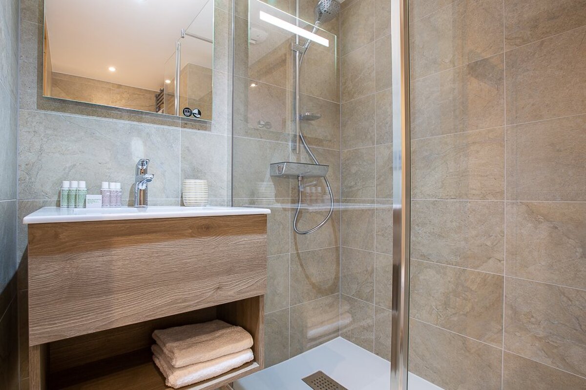 A bathroom with a walk in shower and a sink