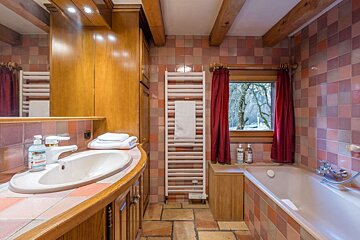 A bathroom with pink tile walls and a tub