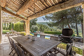 A patio with a table and chairs and a grill
