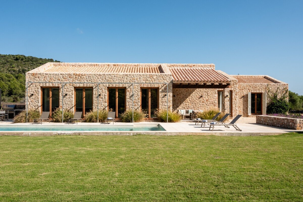 A large stone house with a swimming pool in front of it