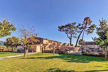 A stone wall surrounds a lush green lawn in front of a house