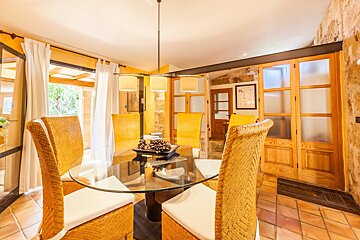 A dining room with wicker chairs and a glass table