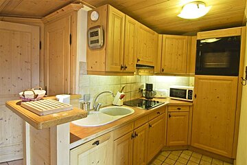 A kitchen with wooden cabinets and a clock on the wall that says ' thermometer ' on it