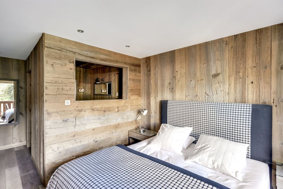 A bedroom with wood paneling and a bed with a checkered headboard