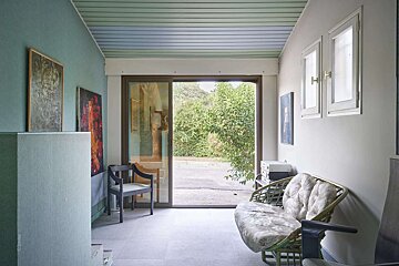 A hallway with a couch and chairs and a sliding glass door