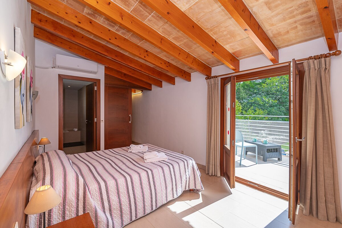 A bedroom with a striped bed and a balcony