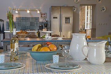 A bottle of wine sits on a table next to a bowl of fruit