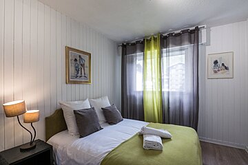 A bedroom with a painting on the wall above the bed