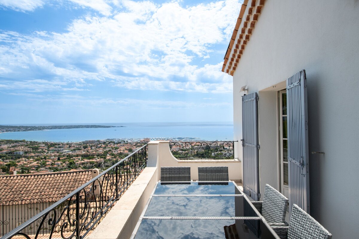 A balcony with a table and chairs overlooking the ocean