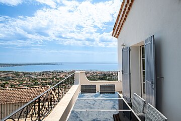 A balcony with a table and chairs overlooking the ocean