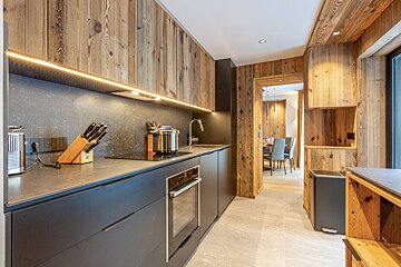 A kitchen with black cabinets and wooden walls