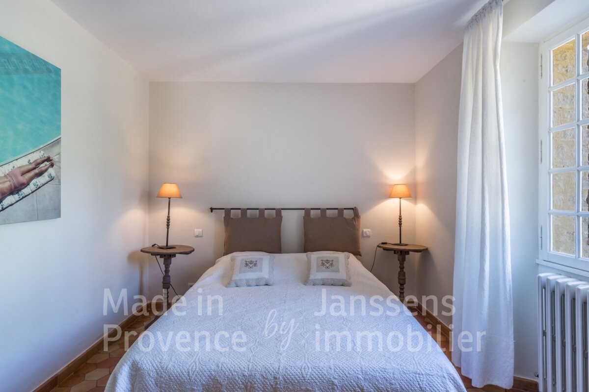 A bedroom with a bed made in provence by janssens immobilier