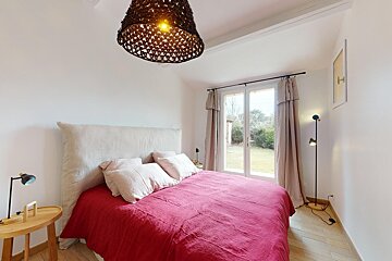 A bedroom with a red bed and a lamp hanging from the ceiling