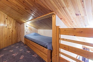 A wooden bed in an attic with a blue blanket
